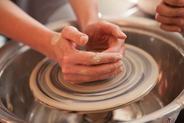 Primo piano delle mani femminili che lavorano sul tornio delle ceramiche