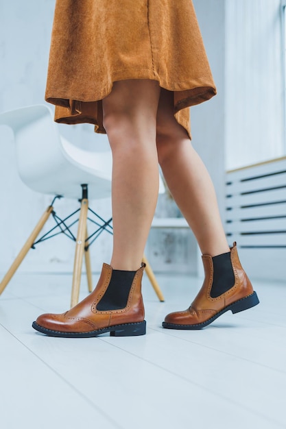 Primo piano di gambe femminili in pelle marrone chelsea boots nuova collezione autunno di scarpe da donna in pelle 2022