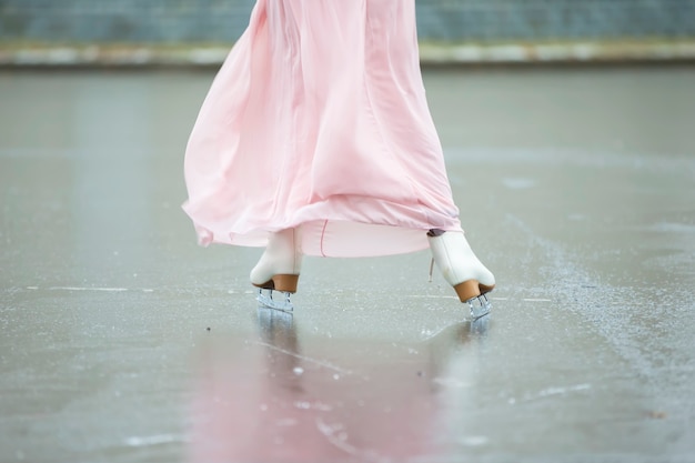 Close-up of female legs on white figure skates in winter at an outdoor ice rink.