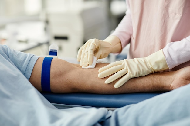 Foto primo piano di un'infermiera che prepara il giovane per la donazione di sangue o lo spazio per la copia della trasfusione