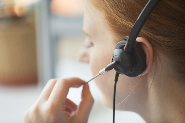 クライアントと話すためにヘッドフォンを使用してコールセンターの女性オペレーターのクローズアップ