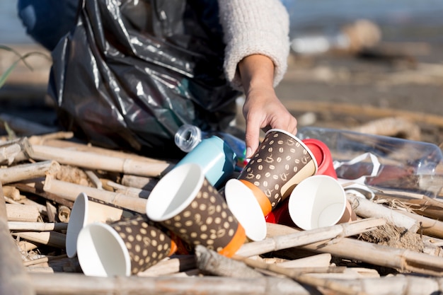 Photo close-up female picking trash from seaside