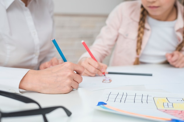 Photo close-up of female psychologist drawing with girl on drawing paper over table