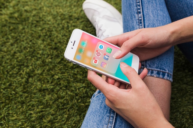 Photo close-up of female's hand holding mobile with social media app on screen