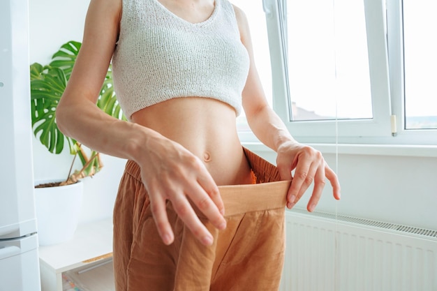 Close up of a female slim waist in old jeans after successful diet indoors