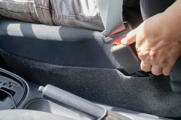 Close up female unfastens car seat belt with her hand in car Safety and transport concept