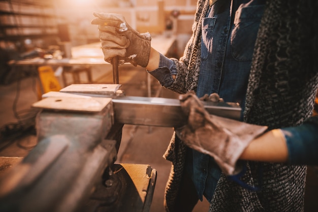 Foto chiuda su della lavoratrice che fa il lavoro del ferro in officina.