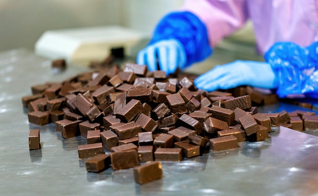 Close up of female worker hands sorts chocolate candies line production at factory