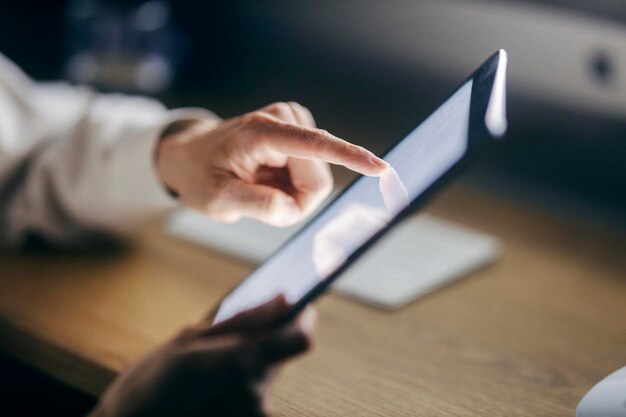 Close up of female39s hand scrolling on tablet in dark room