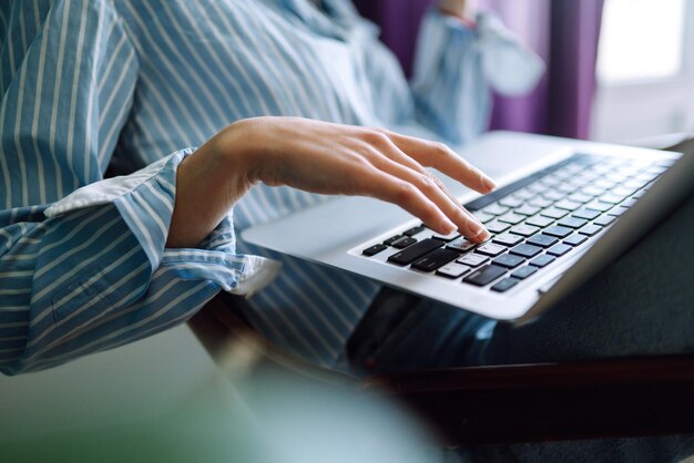 Close up of females hands on the keyboard. Young female freelancer working at home using laptop.