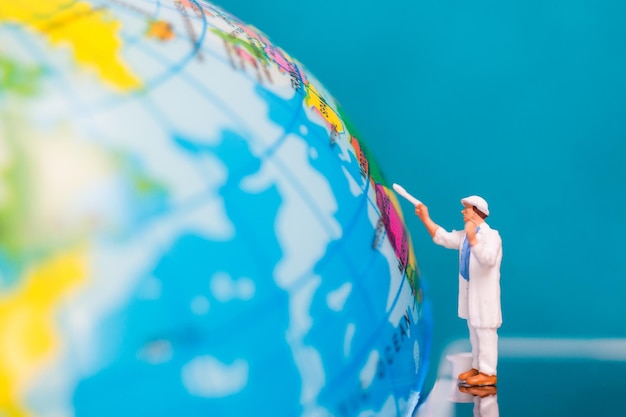 Photo close-up of figurine by globe against blue background