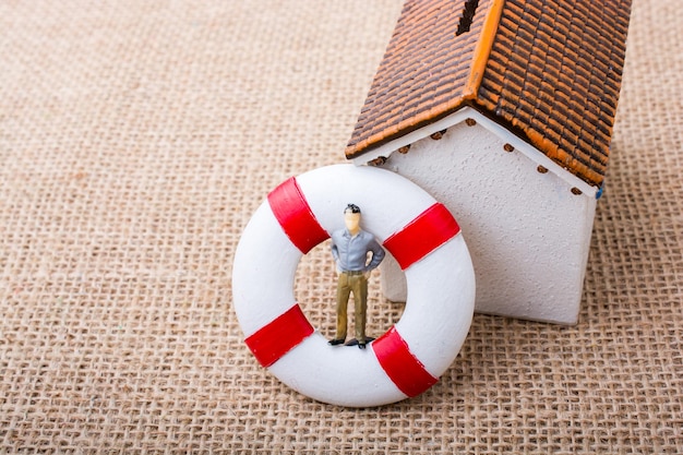 Close-up of figurine by house model on burlap