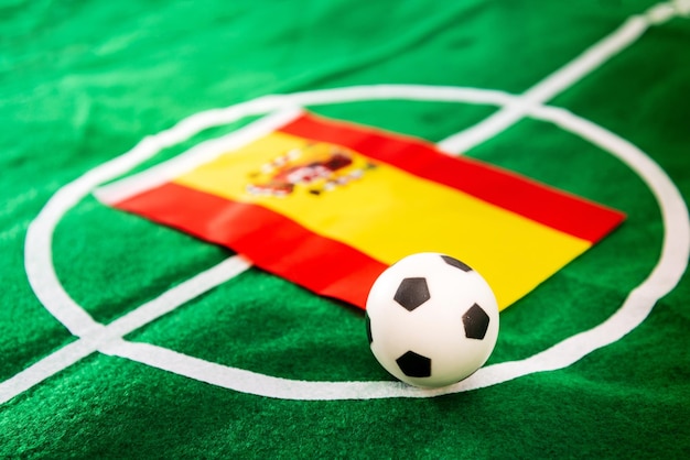Close-up of figurine soccer ball with spanish flag on playing field