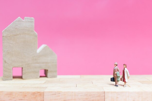 Photo close-up of figurines with model home on table against pink background