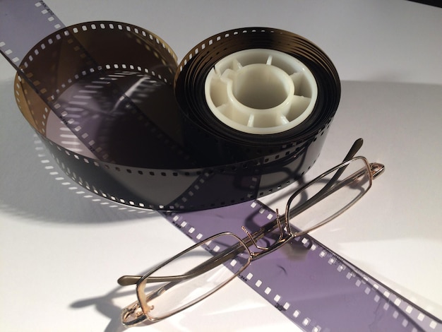 Photo close-up of film reel and eyeglasses on table