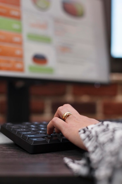 Close up of financial agency office worker on computer, developing marketing strategy while using keyboard. Advertising company businesswoman working on business project and department management.