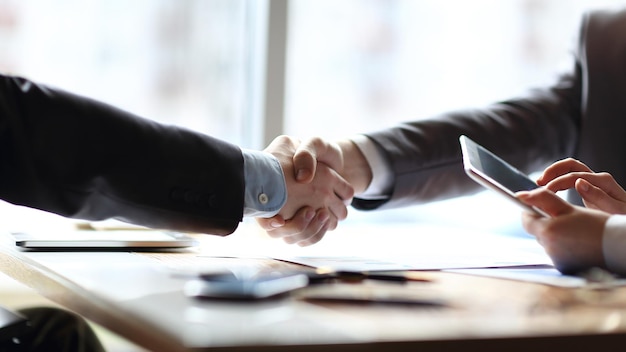 Close up the financial partners shaking hands over a desk