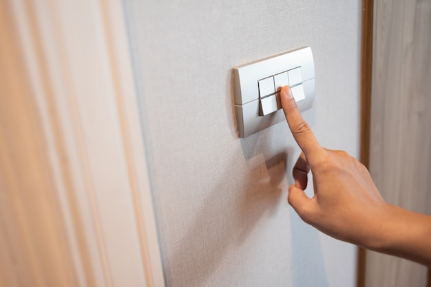 Close up of finger is turning on or off in light switch.