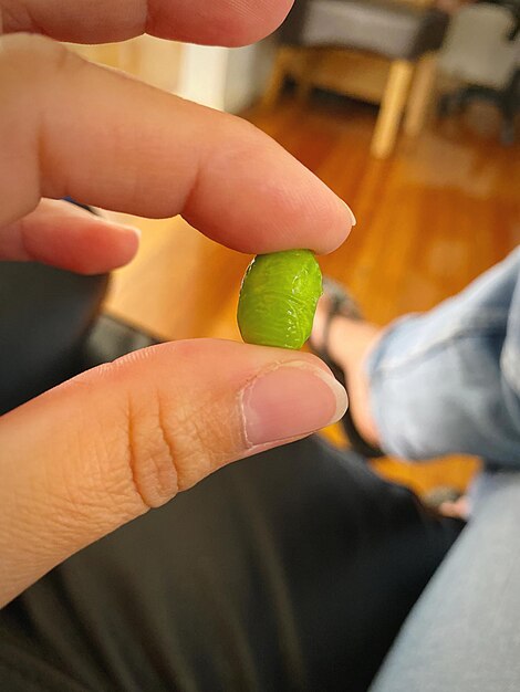 Close-up of fingers holding a edamame