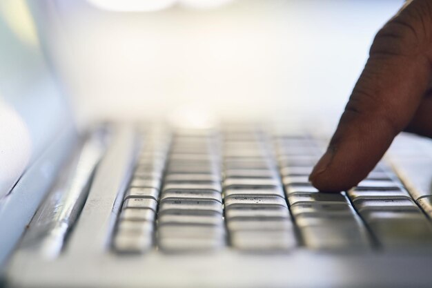 Close up of fingers typing on silver laptop keyboard selective focus