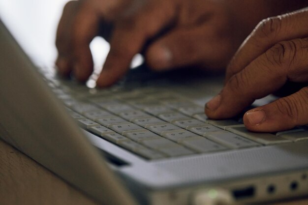 Foto close up delle dita che scrivono sulla tastiera d'argento del portatile con messa a fuoco selettiva
