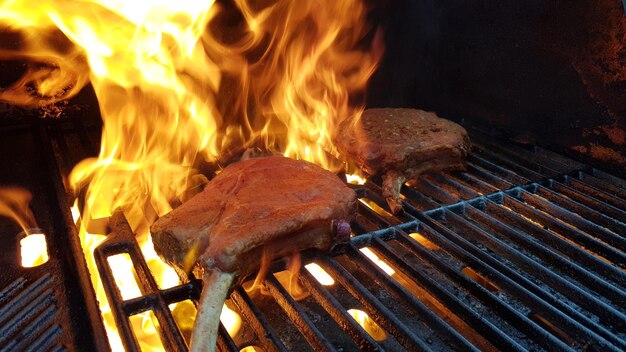 Foto close-up del fuoco sul barbecue grill wirh bistecche tomahawk