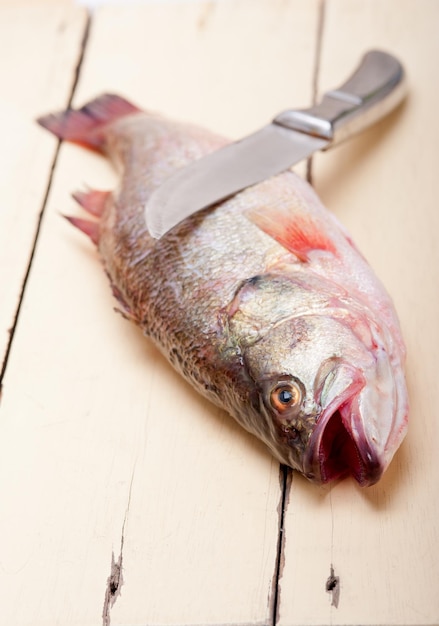 木製のテーブルの上の魚とナイフのクローズアップ