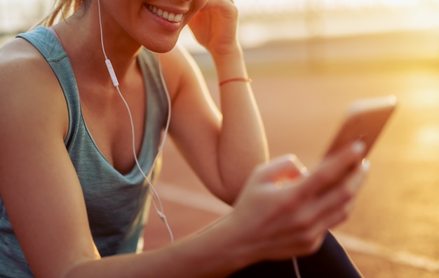 Foto primo piano di una ragazza in forma ascoltando la musica sul suo telefono.