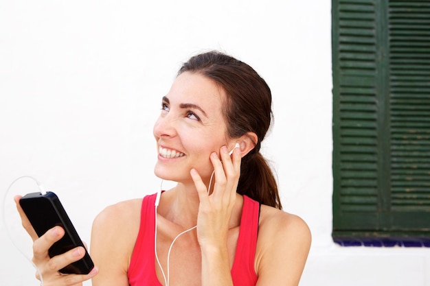 Close up fit young woman relaxing with mobile phone and earphones after workout session