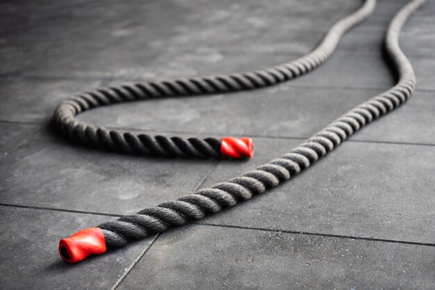 Close up of fitness battle ropes lie on black floor in fitness gym.