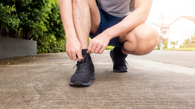 Close up of fitness man is tie shoes 