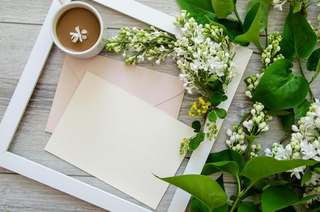 Close-up flatlay met een kopje koffie in wit houten frame en pastelroze enveloppen