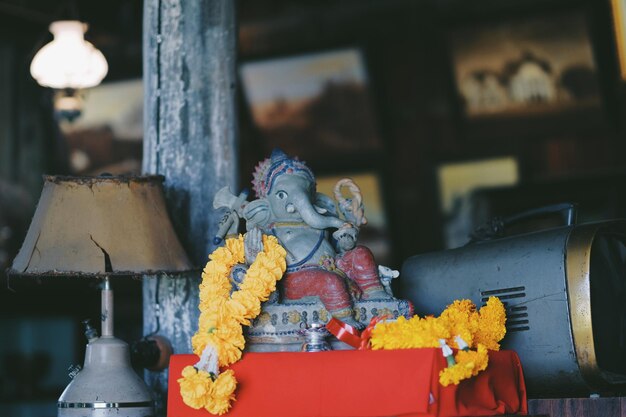 Photo close-up of floral garlands with ganesha sculpture on table