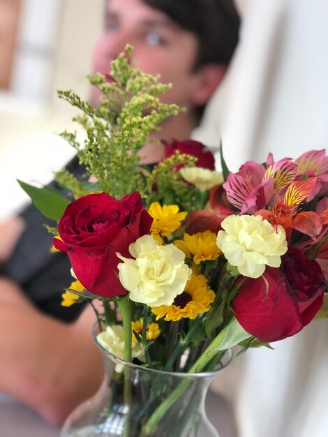 Foto close-up di un vaso di fiori con un giovane uomo sullo sfondo a casa