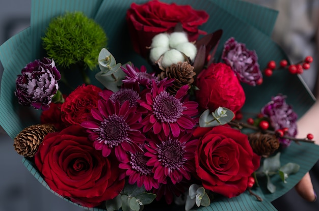 Close-up flowers in hand. Florist workplace. Woman arranging a bouquet with roses, chrysanthemum, carnation and other flowers.