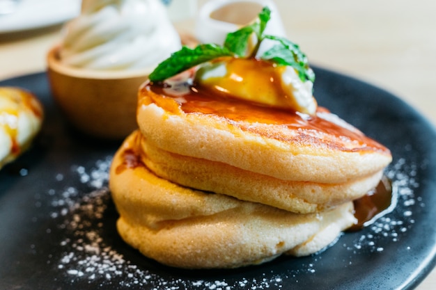 Close up Fluffy pancakes served with caramel banana, ice cream and syrup.