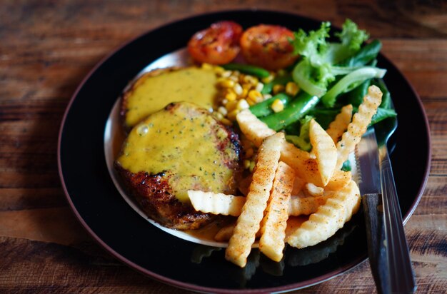 Close up and Focus on French Fries in the Steak main dish in black dish on wood table with the nature light