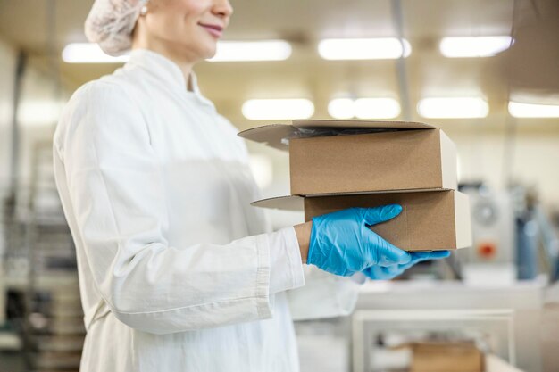 Photo close up of food factory worker carry boxes in facility