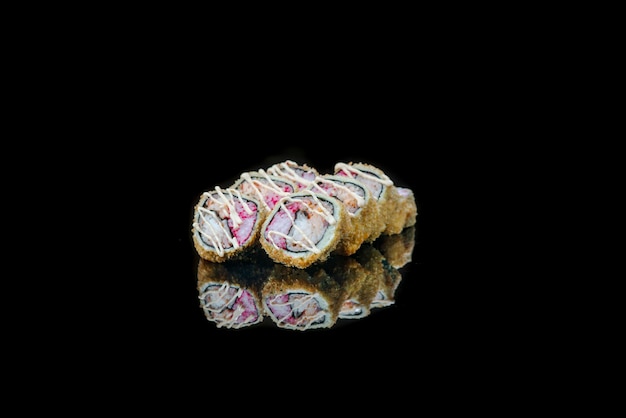 A close up of food fried sushi rolls isolated on black reflection