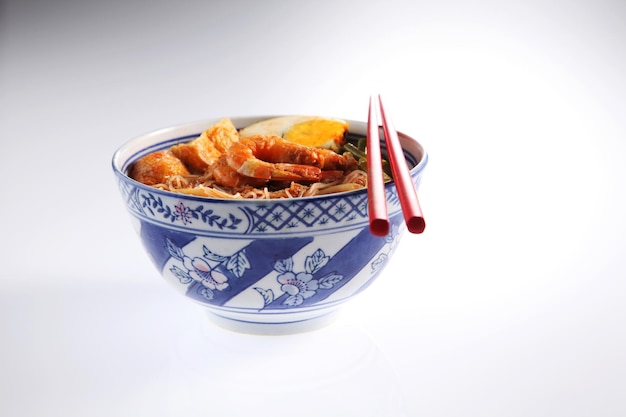 Close-up of food with chopsticks in bowl against white background