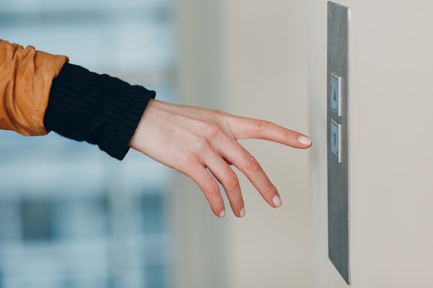 Close up of forefinger pressing the button elevator during coronavirus pandemic covid quarantine concept