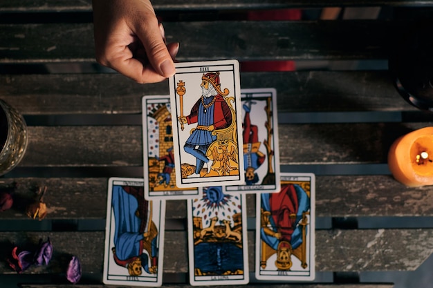 Close-up of a fortune teller displaying some tarot cards on a wooden table