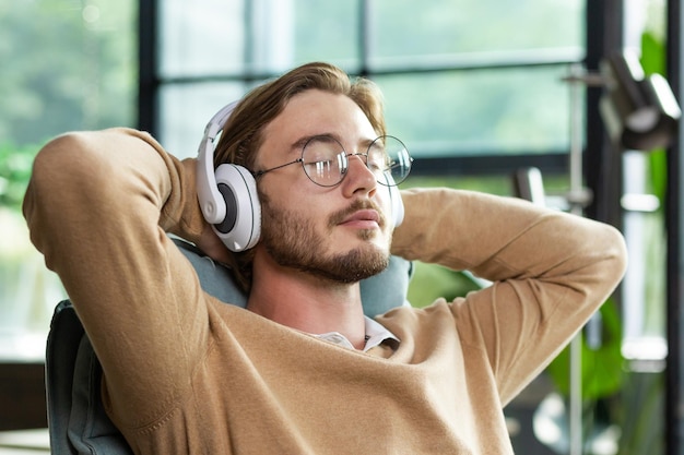 Close-up foto een jonge freelancer een programmeur zit op kantoor met witte koptelefoonhanden