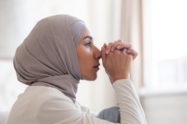 Close-up foto portret van jonge moslimvrouw in hijab die er serieus en verdrietig uitziet, zit hij peinzend