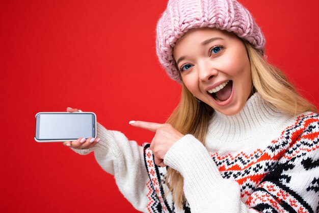 Close-up foto van aantrekkelijke verbaasde lachende jonge blonde vrouw met warme gebreide muts en winter