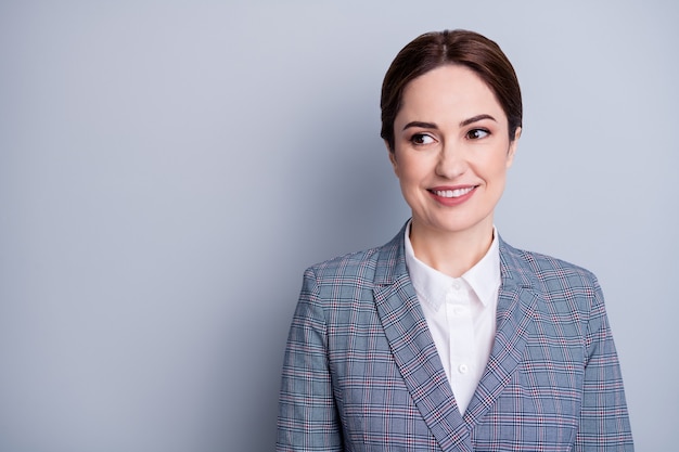 Close-up foto van aantrekkelijke zakelijke dame stralende glimlach goed humeur geschoolde leraar beroep bezetting kijk geïnteresseerd kant slijtage geruite blazer wit overhemd geïsoleerd grijze kleur achtergrond