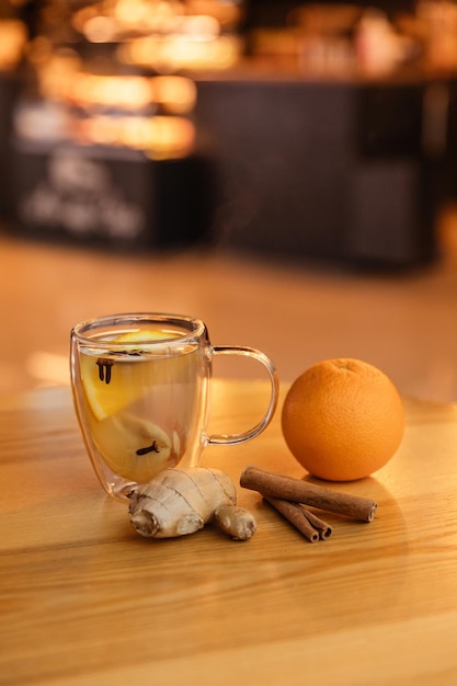 Close-up foto van een helder glas gemberthee op een tafel in een café Oranje gember en kaneel als ingrediënten van de drank Gezondheidsthee