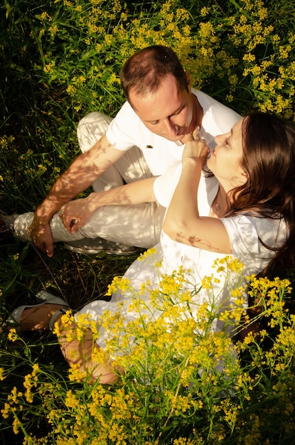 Close-up foto van een jong stel ontspannen in het gras en gele bloemen