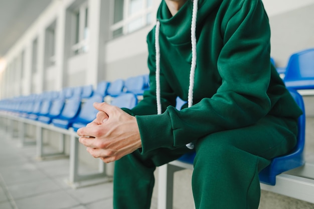 Close-up foto van een jonge man 39s hand in een groen pak zit op de tribunes en doet pijn