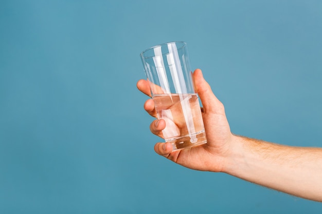 close-up foto van een jonge roodharige man in een wit t-shirt drinkwater uit een glas.